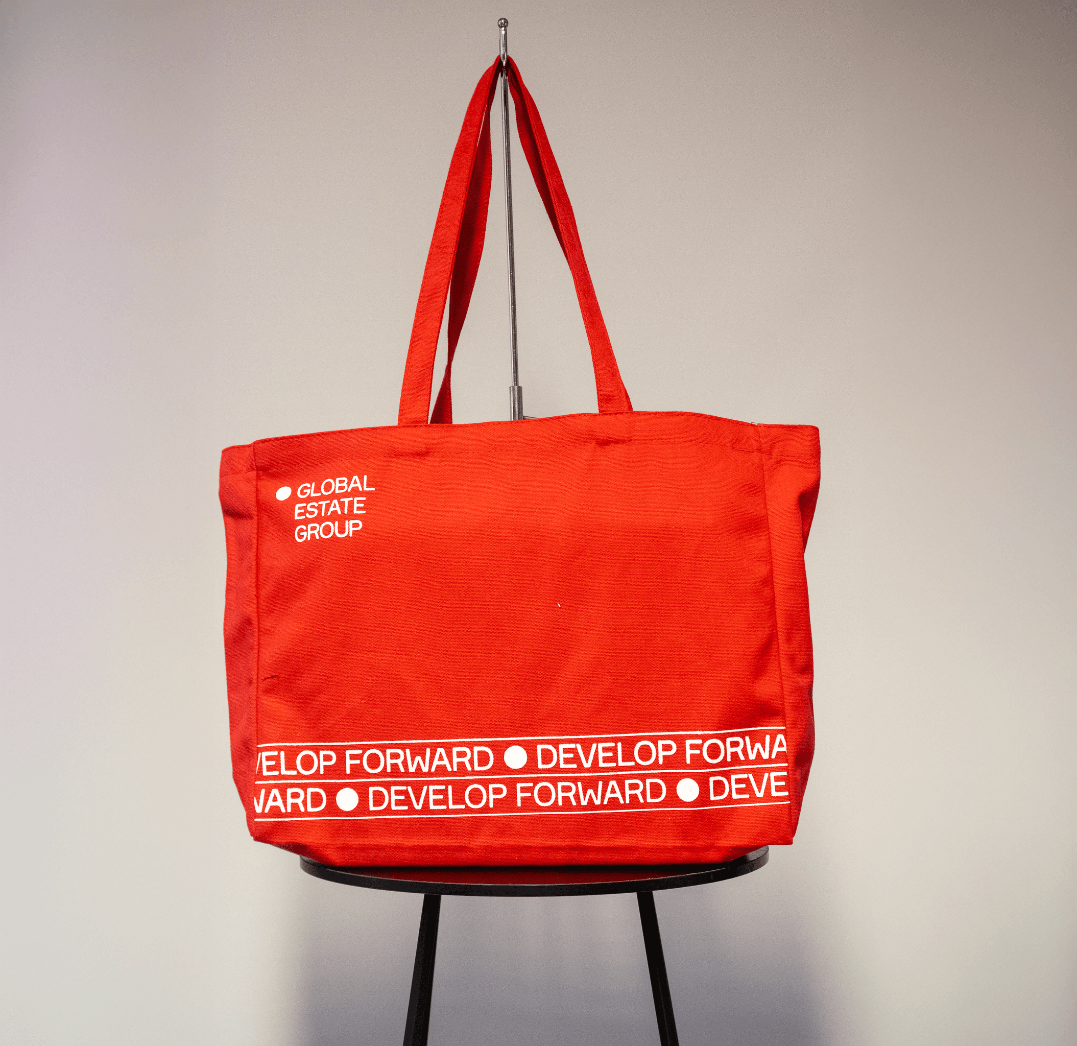 Rode katoenen draagtas met witte opdruk ‘Global Estate Group’ en slogan ‘Develop Forward